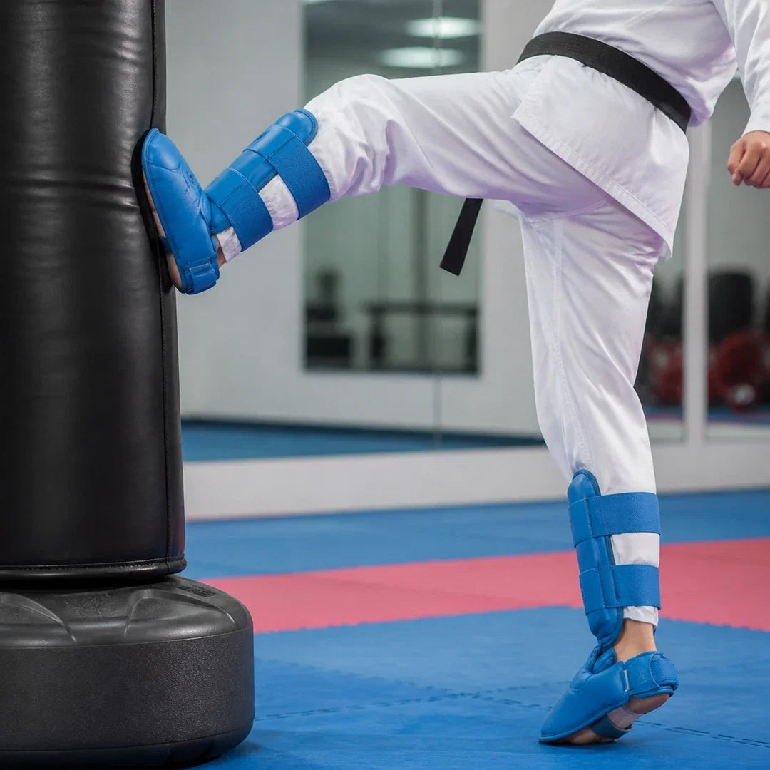 Caneleira Endurafit azul sendo usada em chute de taekwondo no saco de treino
